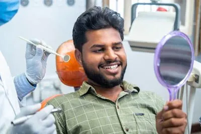 patient looking at his teeth in a mirror after getting them cleaned at Hymas Family Dental